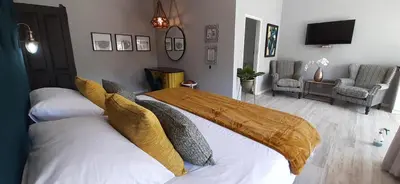 a bedroom with a bed with white sheets and yellow pillows at La Roca Guest House in Nelspruit