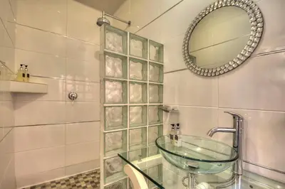 a bathroom with a glass sink and a mirror at La Roca Guest House in Nelspruit