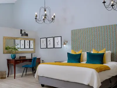 a bedroom with a bed with blue pillows and a desk at La Roca Guest House in Nelspruit
