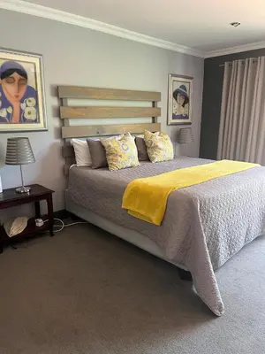a bedroom with a large bed with a yellow blanket at Koru Guesthouse in Pretoria