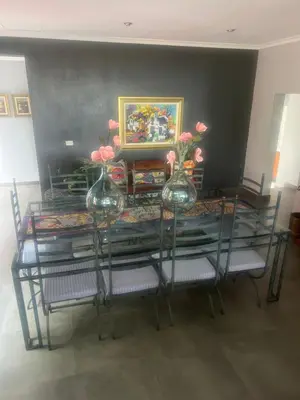 two vases with flowers on a glass table with chairs at Koru Guesthouse in Pretoria