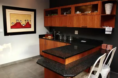 a kitchen with a black counter top and wooden cabinets at Koru Guesthouse in Pretoria