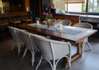 a wooden table with wicker chairs in a kitchen at Koru Guesthouse in Pretoria