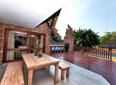 a wooden deck with a table and benches on it at Kruger Park Lodge Unit No. 509 in Hazyview