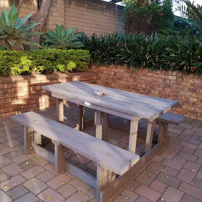 a wooden picnic table sitting next to a brick wall at Falling Feather Inn in Pretoria
