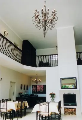 a dining room with a table and chairs and a chandelier at Falling Feather Inn in Pretoria