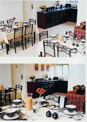 a dining room with a table with plates and candles at Falling Feather Inn in Pretoria