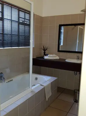 a bathroom with a tub and a sink at Falling Feather Inn in Pretoria