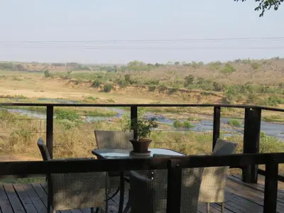a table and chairs on a deck with a view of a river at Kruger View Tree House in Marloth Park