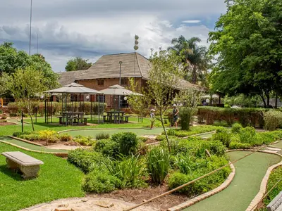 a garden with a building with a bench and tables at Mount Amanzi in Hartbeespoort