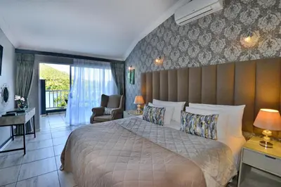 a bedroom with a large bed and a chair at The Shore House in Hartbeespoort