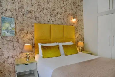 a bedroom with a bed with a yellow headboard and two lamps at The Shore House in Hartbeespoort