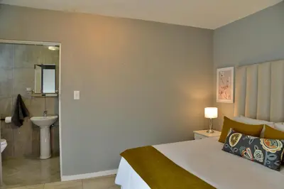 a bedroom with a bed and a bathroom with a sink at The Shore House in Hartbeespoort
