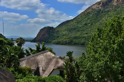 a house in front of a river with mountains at The Shore House in Hartbeespoort