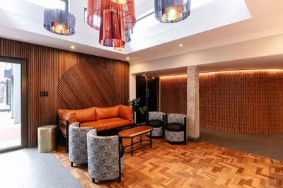 a lobby with an orange couch and stools at Hotel 224 & Apartments in Pretoria