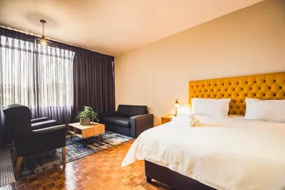 a hotel room with a large bed and a chair at Hotel 224 & Apartments in Pretoria