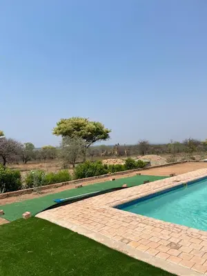 a large swimming pool with green grass and trees at Karibu River Retreat in Marble Hall