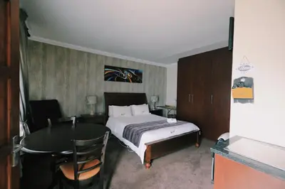 a bedroom with a bed and a table and a desk at Ledumo Guest lodge in Witbank