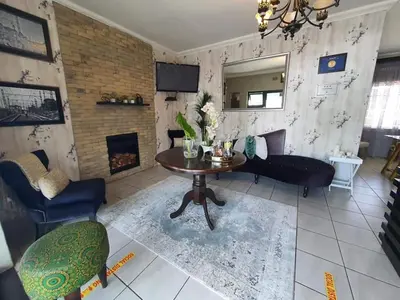 a living room with a table and a fireplace at Ledumo Guest lodge in Witbank