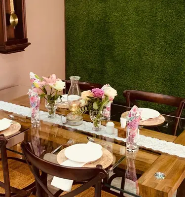 a dining room table with plates and flowers on it at Diamond Rose Guest House in Middelburg