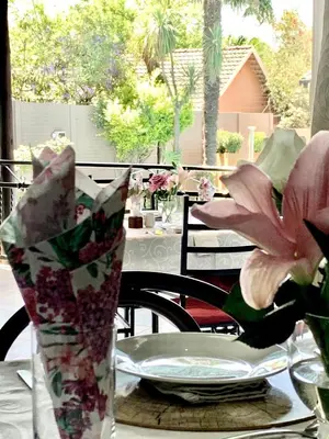 a table with a plate and a vase of flowers at Diamond Rose Guest House in Middelburg