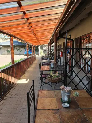 an outdoor patio with tables and chairs and a wooden pergola at Diamond Rose Guest House in Middelburg