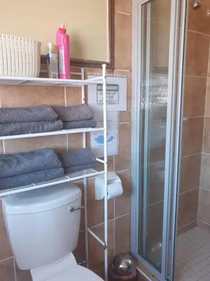 a bathroom with a toilet and a shower with towels at Clearwater Self catering Apartments No Loadshedding in Centurion