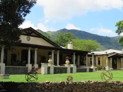 a house with a stone wall in front of it at Dawsons Game Lodge in Badplaas
