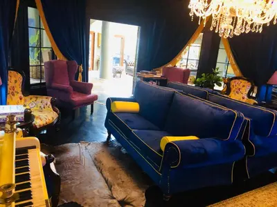a living room with a blue couch and a piano at Shangri-La Country Hotel & Spa in Modimolle