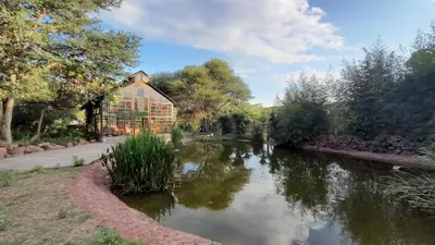 a house with a pond in front of a building at Shangri-La Country Hotel & Spa in Modimolle