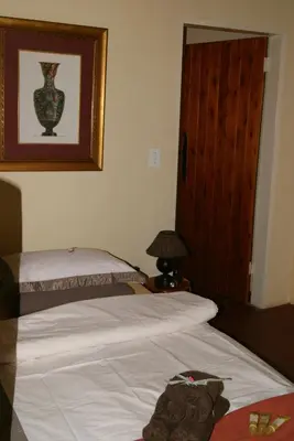 a bedroom with two beds and a door and a lamp at Weltevreden Country Guest Lodge in Groblersbrug