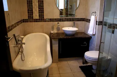 a bathroom with a tub and a sink and a toilet at Goodey's Guesthouse in Pretoria