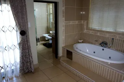 a bath tub in a bathroom with a window at Goodey's Guesthouse in Pretoria