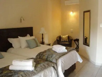 a hotel room with two beds and a chair at Goodey's Guesthouse in Pretoria