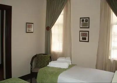 a bedroom with two beds and a chair and a window at Goodey's Guesthouse in Pretoria