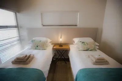 two twin beds in a room with a table at Maya Manor in Hoedspruit