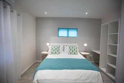 a bedroom with a bed and two tables and shelves at Maya Manor in Hoedspruit