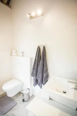 a white bathroom with a toilet and a sink at Maya Manor in Hoedspruit