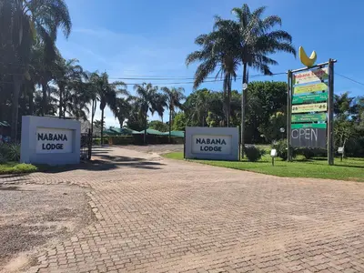 two signs in a park with palm trees in the background at Nabana Lodge in Hazyview