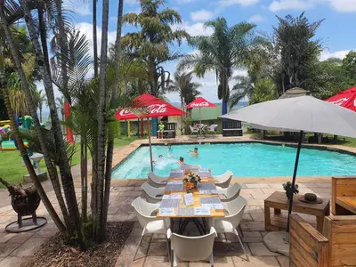 a pool with a table and chairs and an umbrella at Nabana Lodge in Hazyview