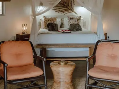 a bedroom with a bed and two chairs at Nyala Safari Lodge in Hoedspruit
