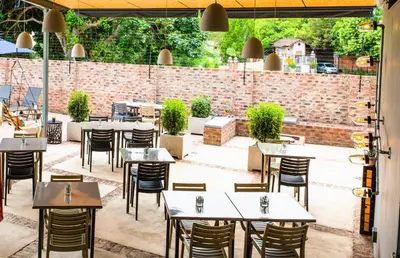 a restaurant with tables and chairs and a brick wall at Execustay in Nelspruit