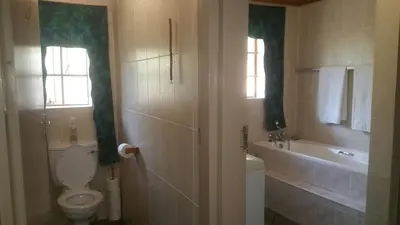 a bathroom with a toilet and a tub and a sink at Marlothii Safari House in Marloth Park