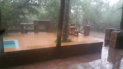 a rain soaked patio with a table and a picnic table at Marlothii Safari House in Marloth Park