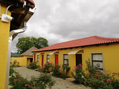 a row of yellow and red buildings with flowers at Kanyane Lodge in Jane Furse