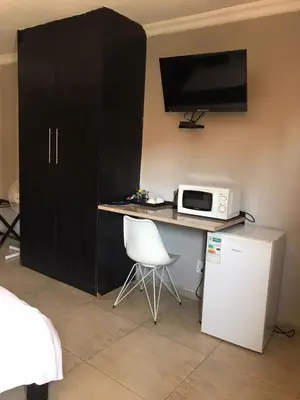 a kitchen with a desk with a microwave and a tv at Kanyane Lodge in Jane Furse