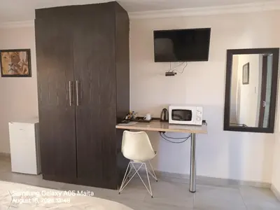 a room with a desk with a microwave and a cabinet at Kanyane Lodge in Jane Furse