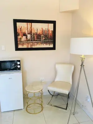 a living room with a chair and a refrigerator at Riverton Manor in Centurion