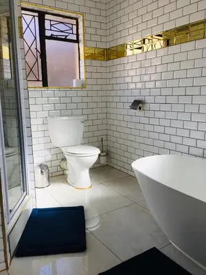 a bathroom with a toilet and a tub and a sink at Riverton Manor in Centurion