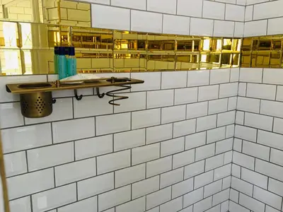 a bathroom with white tiled walls and a mirror at Riverton Manor in Centurion